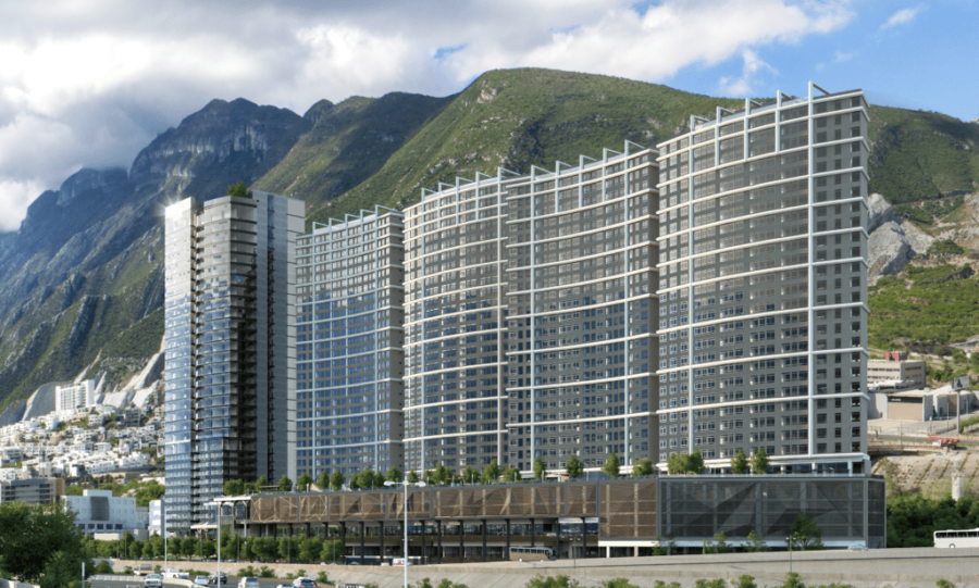 A large building covered in windows, with mountains in the background.